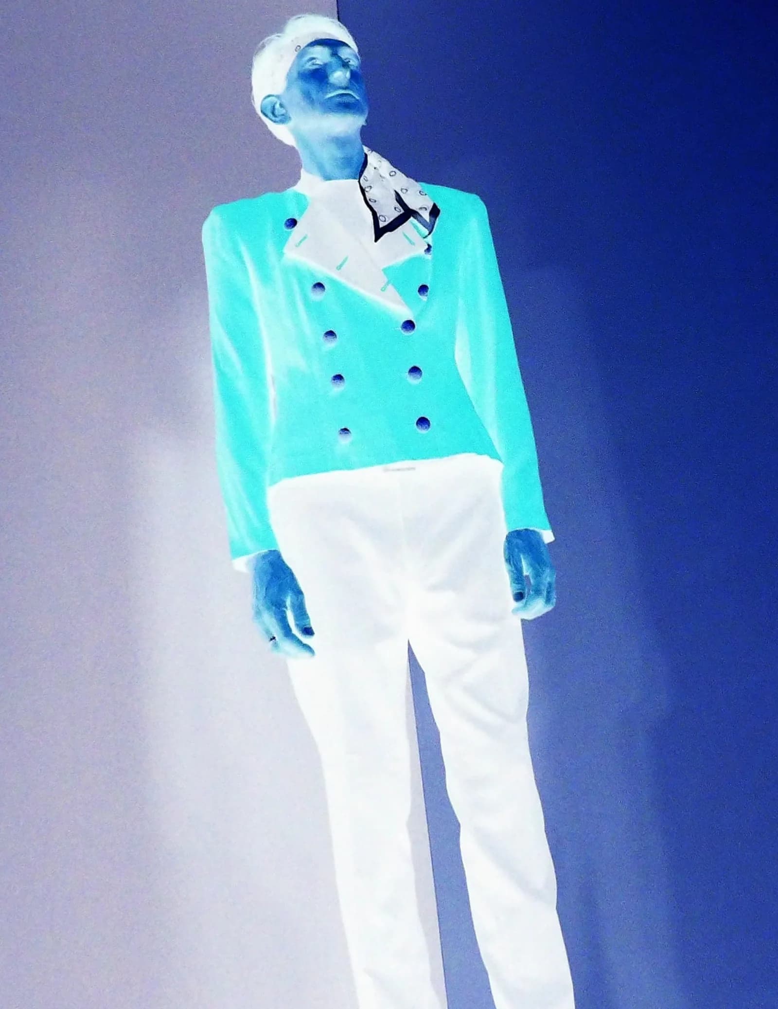 Notorious frontman in a teal double-breasted blazer under blue stage lights