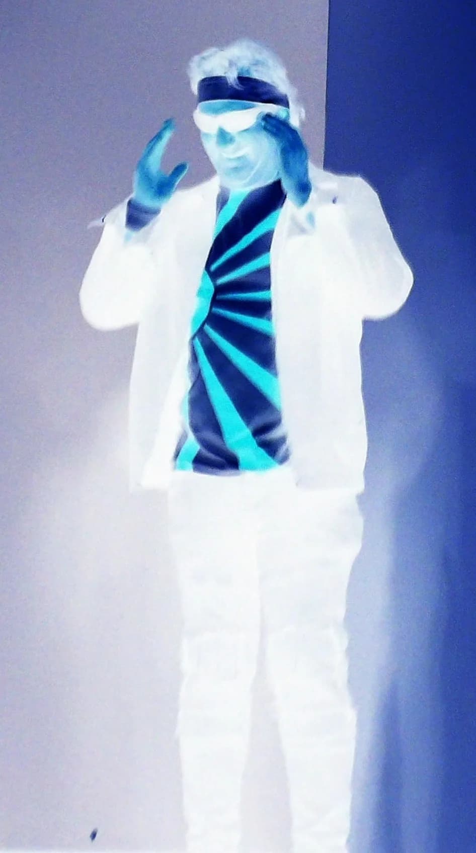 Notorious vocalist striking a dramatic pose in white suit under blue-white stage wash